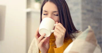 person drinking out of a ceramic mug