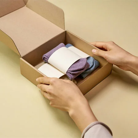 A Person Packaging Folded Socks with a Cardboard Box
