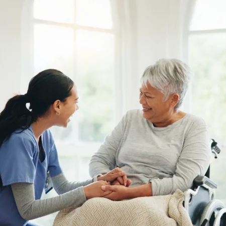 Nurse and older adult holding hands.