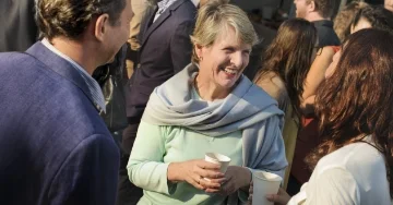 Three people standing at an event smiling and talking
