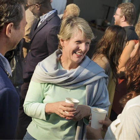 Three people standing at an event smiling and talking.