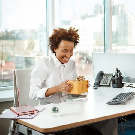 person sitting at a desk holding a gift