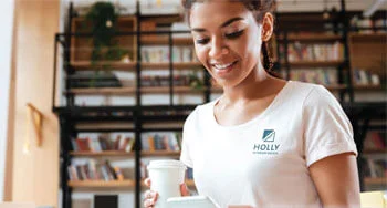 person holding a cup of coffee looking at a phone