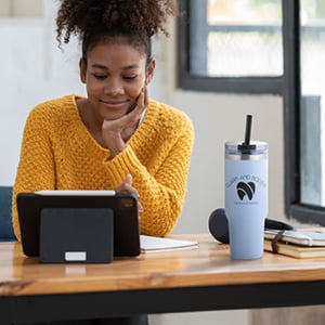 Woman sitting at a desk drinking out of water bottle