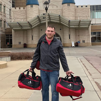Man holding two duffel bags with his company logo on them