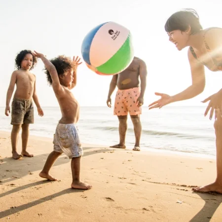 Family playing with a beach ball on the beach.