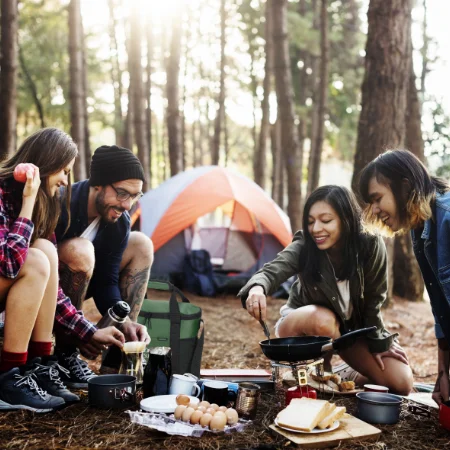 Group of friends cooking over a campfire.