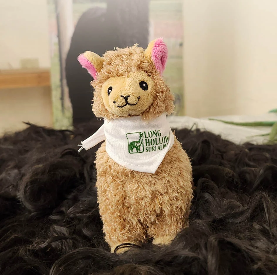 plush alpaca toy wearing a logoed bandana