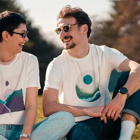 two people wearing printed t-shirts sitting on grass