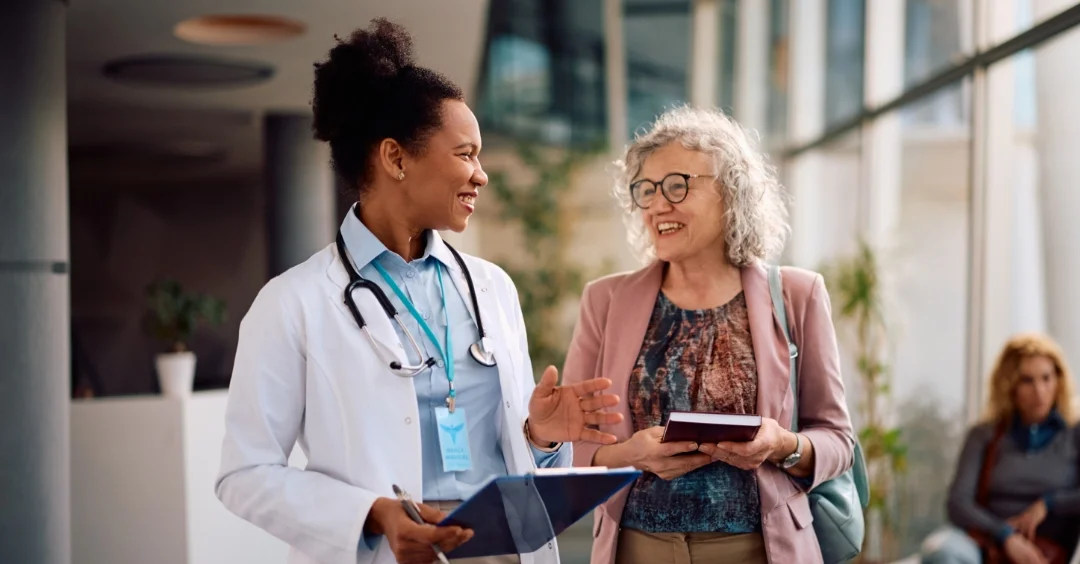 Doctor walking and talking with a smiling patient.