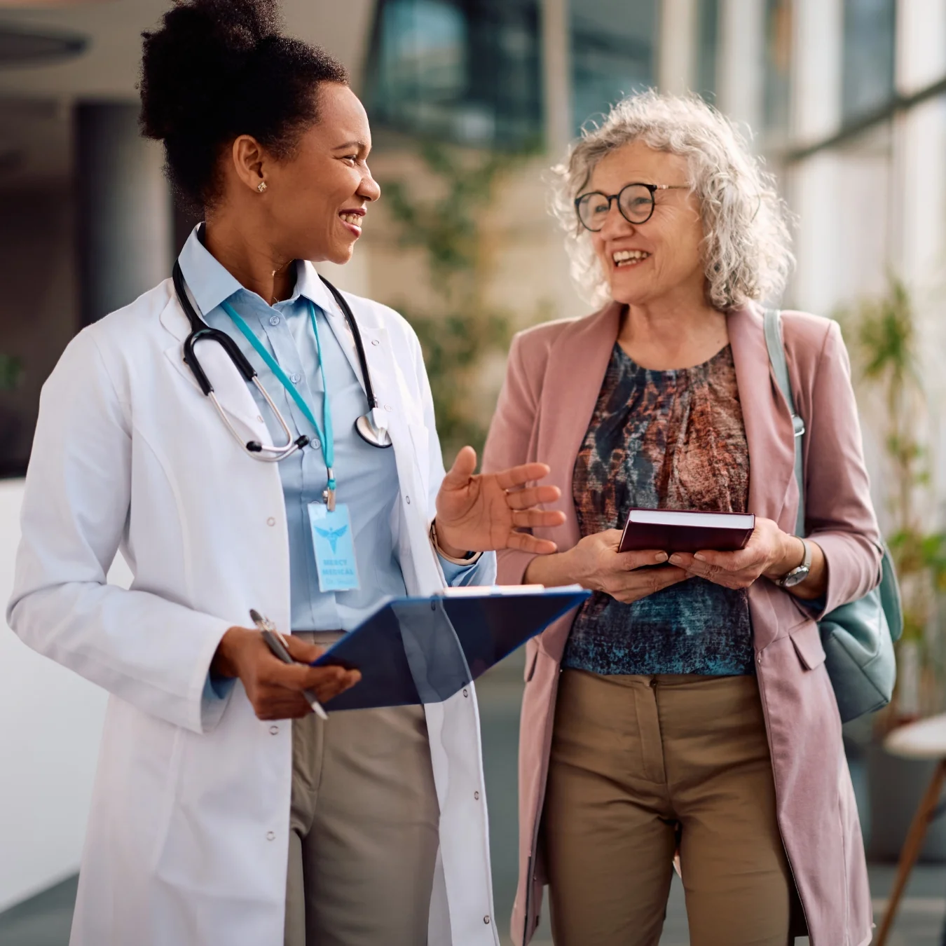 Doctor walking and talking with a smiling patient.
