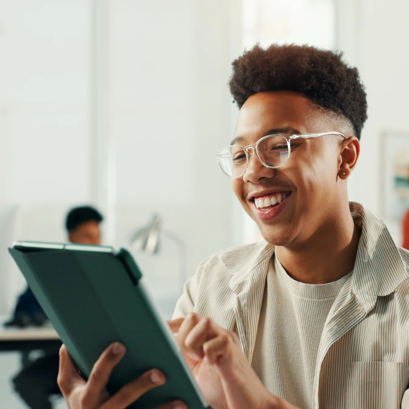 Smiling person working on a tablet in an office setting.