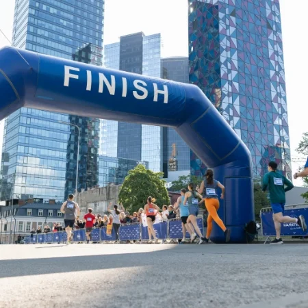 Group of people running across a race finish line.
