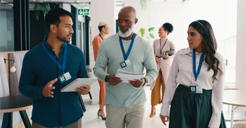 people talking wearing lanyards, possibly in an office or tech show environment.