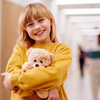 Small girl holding on to a stuffed teddy bear