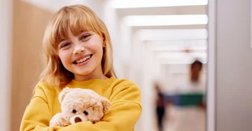 Small girl holding on to a stuffed teddy bear