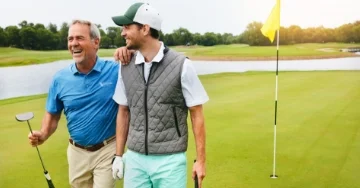 Two golfers walking on the green.