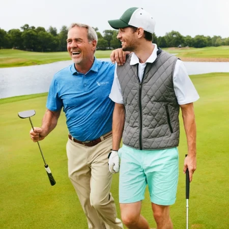 Two golfers walking on the green.