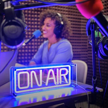 A woman at a radio station with an on air neon sign lit up