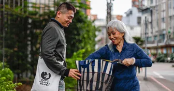 Man and woman walking on the sidewalk with cotton totes