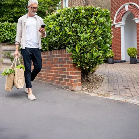 A man walking home with groceries in a tote