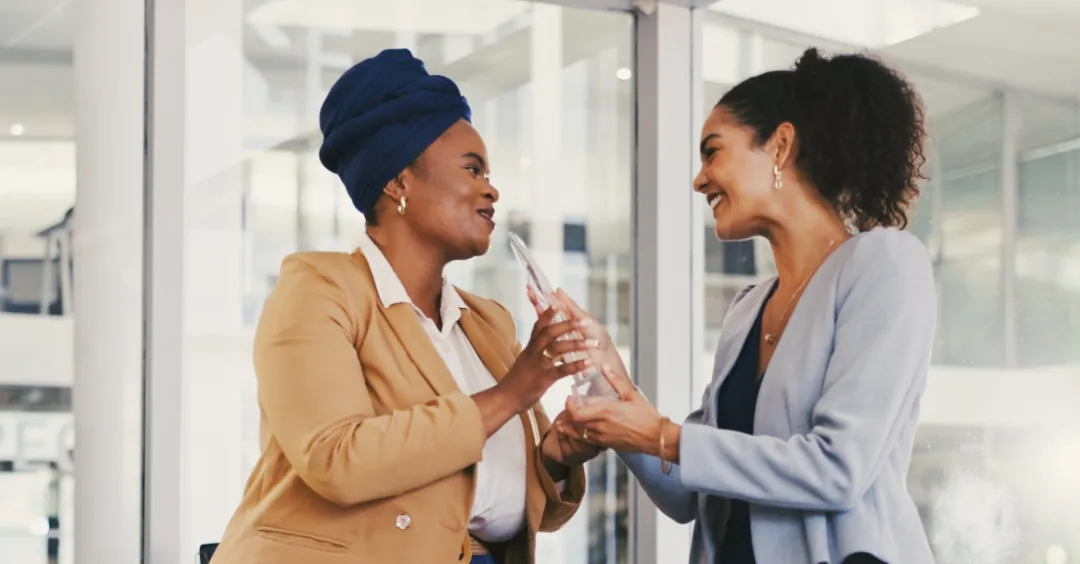 A manager handing a team member a crystal award in an office setting.