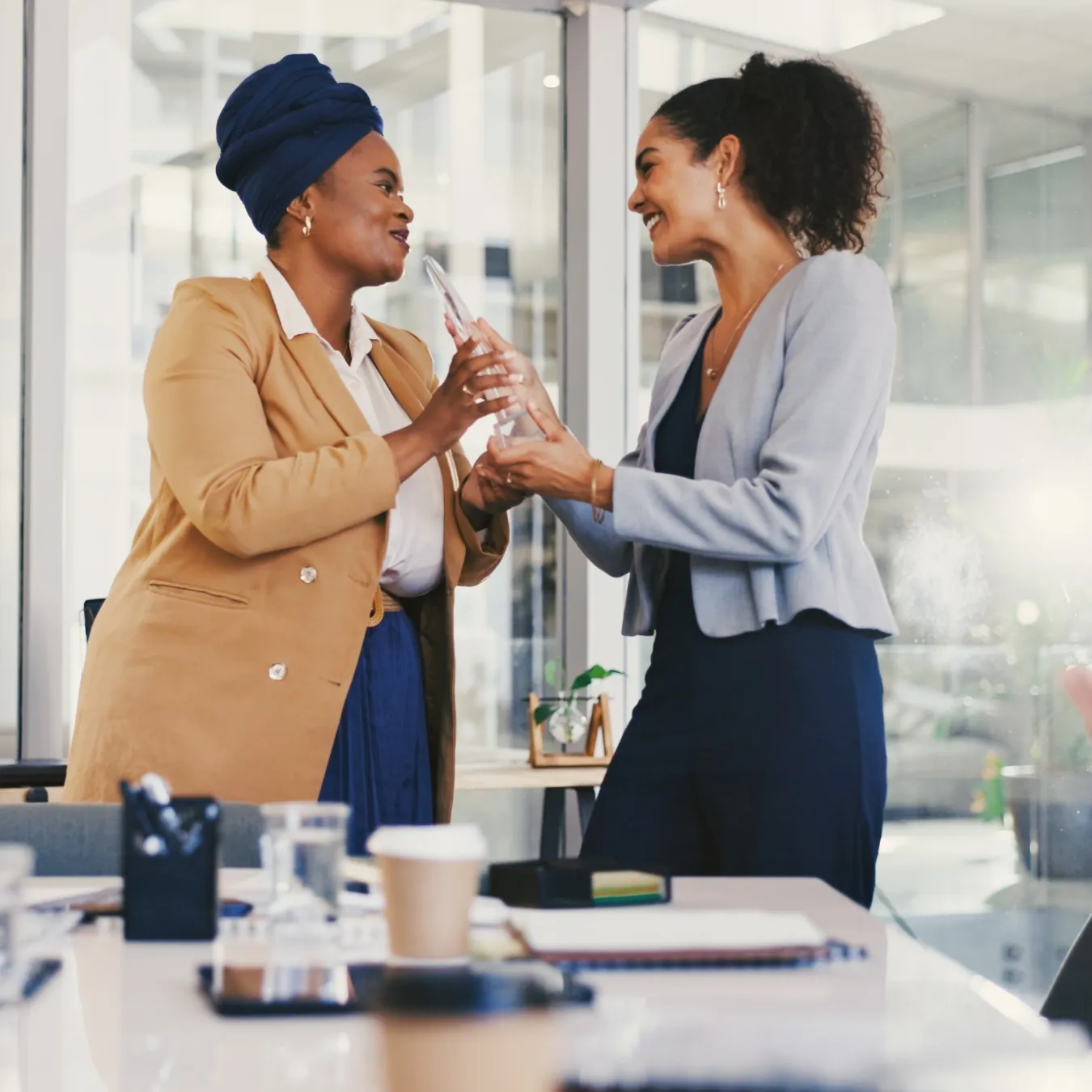 A manager handing a team member a crystal award in an office setting.