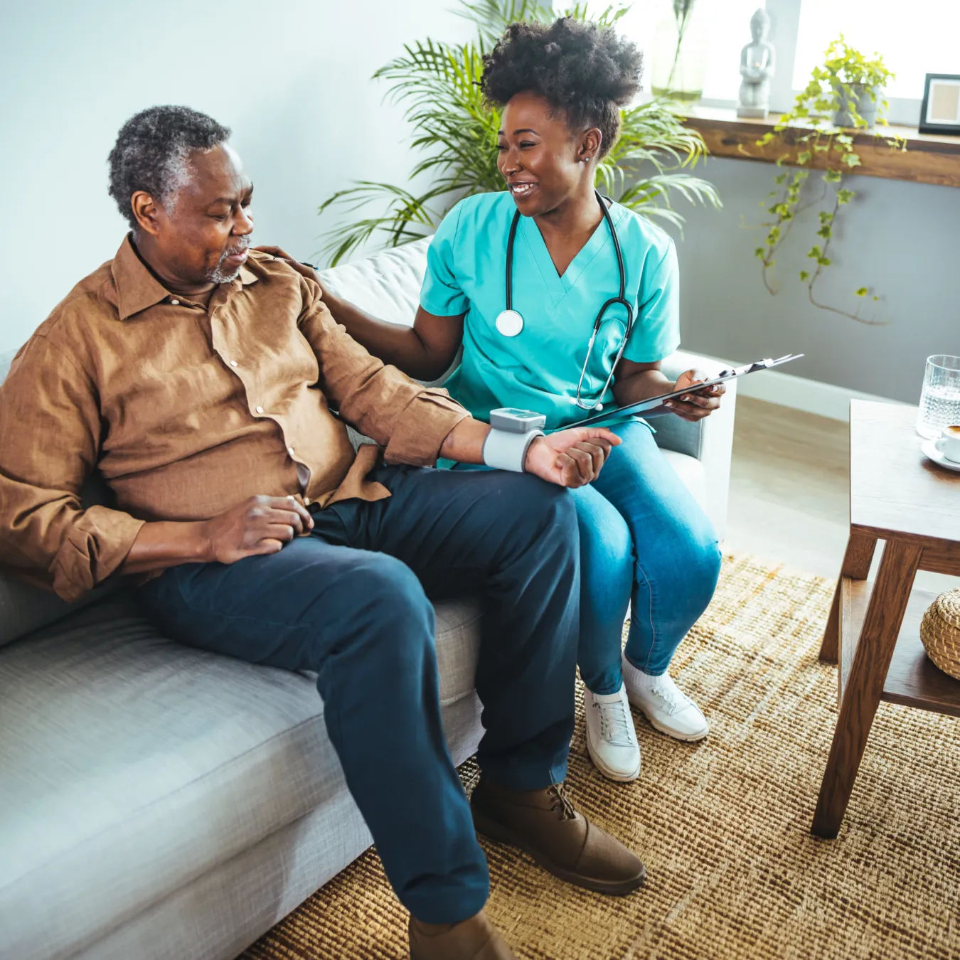 A nurse in scrubs checking on a patient in a home setting.