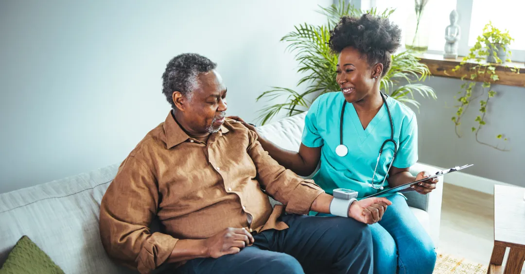 A nurse in scrubs checking on a patient in a home setting.