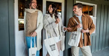 Two men and one woman outside shopping with cotton bags