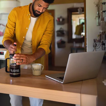 Person in kitchen using French press to make coffee.