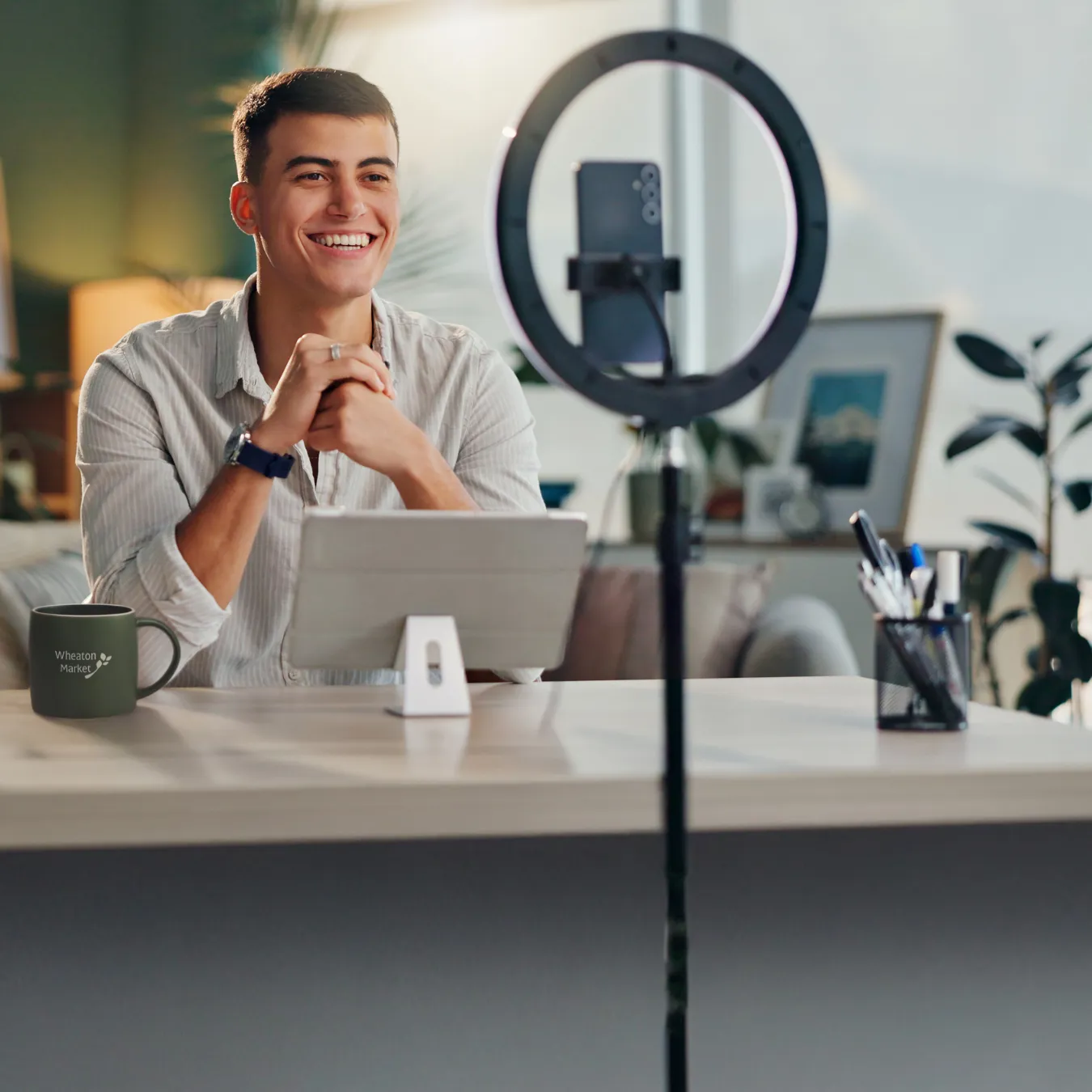 Influencer at home filming with a smartphone and ring light.