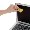 a hand holding a yellow object in front of a laptop