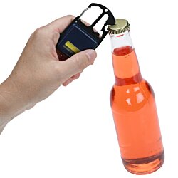a hand holding a keychain over a bottle