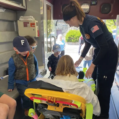A person standing next to a group of children in an ambulance