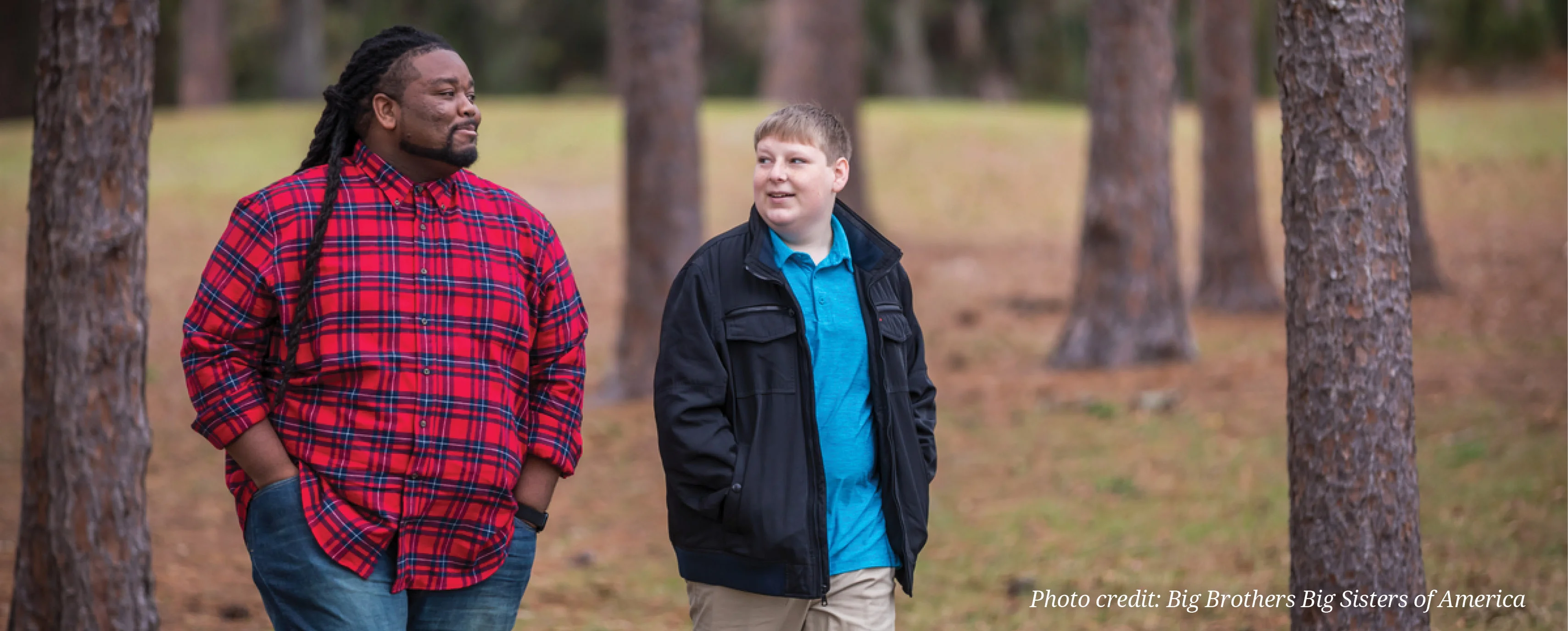 two people walking through a wooded area talking