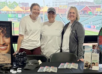 three Red Lion Dental employees standing by a table of promotional products