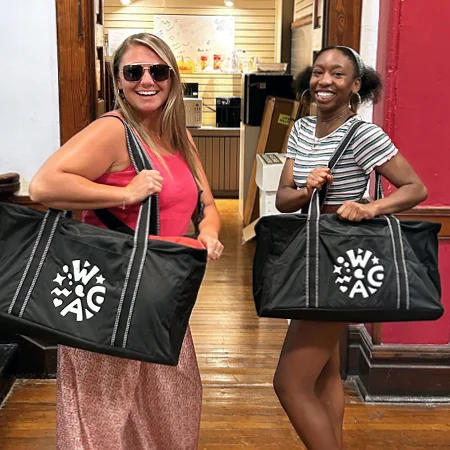 Two women holding bags in a room