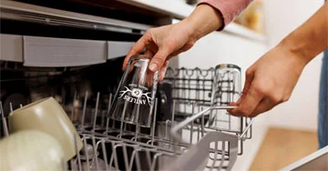 person putting a beer glass into a dishwasher