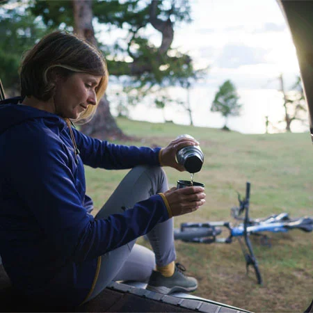 A person pouring coffee from an insulated travel mug