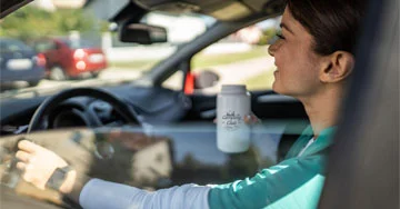 A person holding a bottle in a car