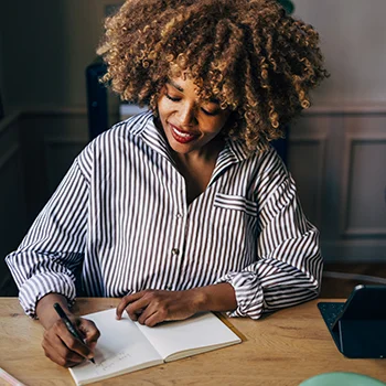 A woman writing in a notebook with a custom pen