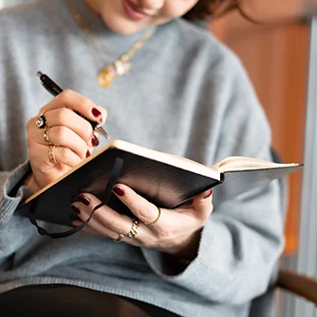 A woman writing in a notebook with a custom pen