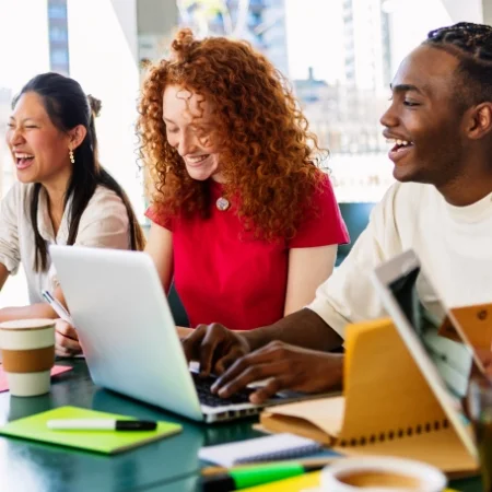 Group of smiling and laughing students together at a table.