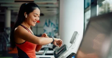 Person using their smart watch while running on a treadmill.