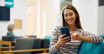 Person sitting in a waiting room scrolling on their phone.