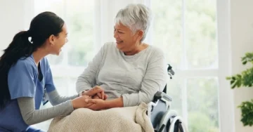 Nurse and older adult holding hands. 