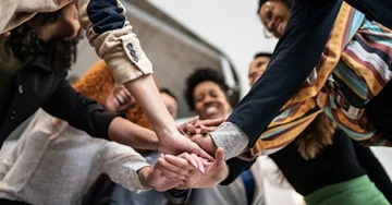 group of workers coming together in a circle with hands in the middle