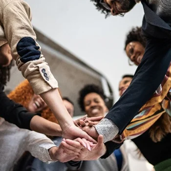 group of workers coming together in a circle with hands in the middle