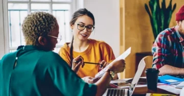 Two people sitting at a table reviewing a document together.